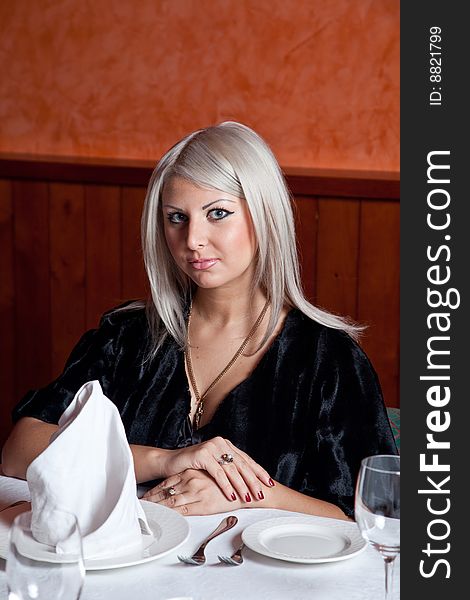 Charming blond girl sitting at a table