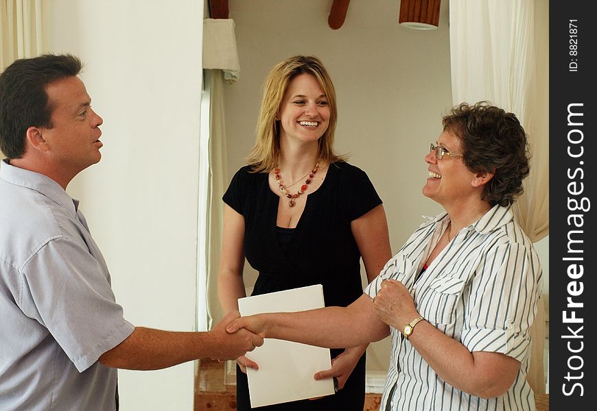 A couple of time share sales people congratulating a happy buyer after showing the accommodations. A couple of time share sales people congratulating a happy buyer after showing the accommodations.