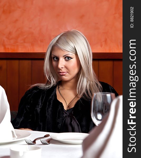 Charming blond girl sitting at a table in a restaurant