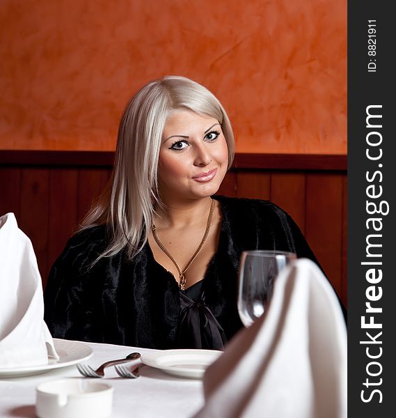 Charming blond girl sitting at a table in a restaurant