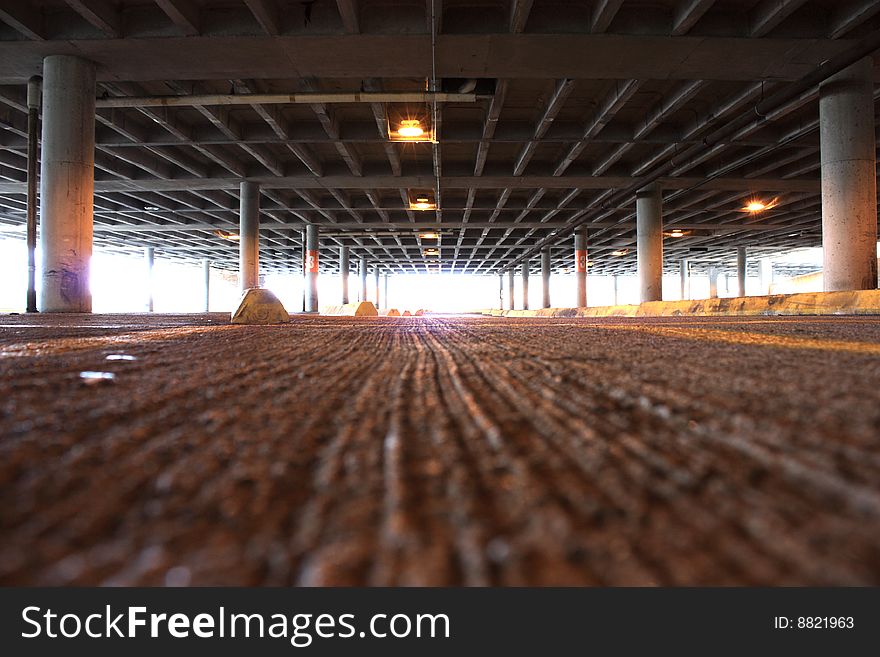 Inside of a vacant parking garage with the sun shining through the two levels. Inside of a vacant parking garage with the sun shining through the two levels.