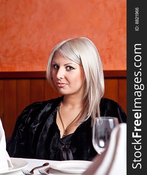 Charming blond girl sitting at a table in a restaurant