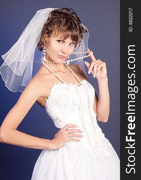 Studio portrait of a young bride wearing a white wedding dress with pearls