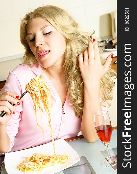 Pretty blond girl at home in the kitchen eating spaghetti. Pretty blond girl at home in the kitchen eating spaghetti