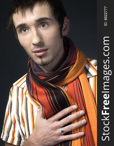 Portrait of a young handsome man with colorful scarf on dark background. Portrait of a young handsome man with colorful scarf on dark background