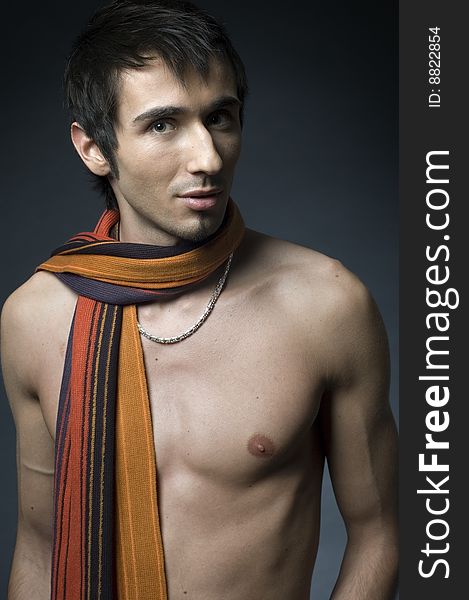 Young fashion male model with athletic body posing in colorful srarf