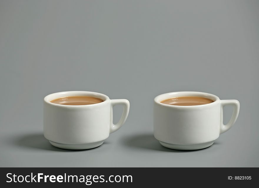 Two white coffee cups on gray background. Two white coffee cups on gray background