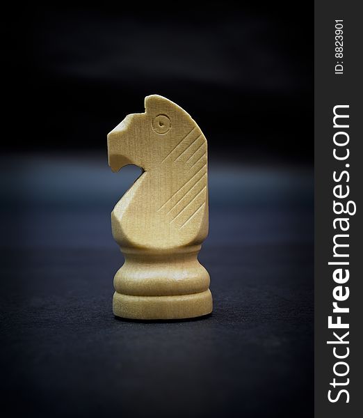 Knight, wooden chess piece isolated on dark background.