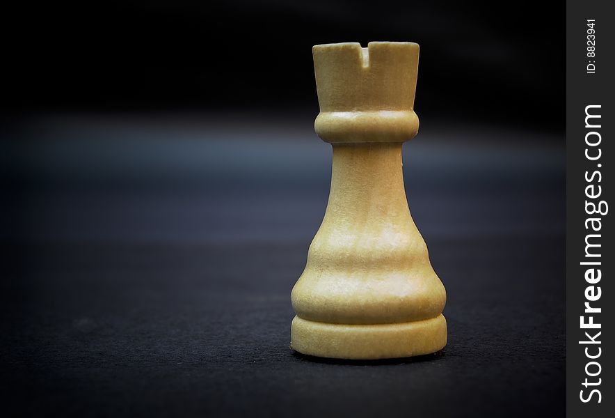Tower, wooden chess piece isolated on dark background.