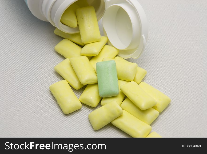 Yellow pills out of container with light background and a different pill