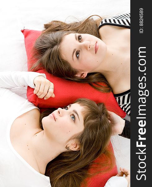 Two beautiful girls lying on red pillows. Two beautiful girls lying on red pillows
