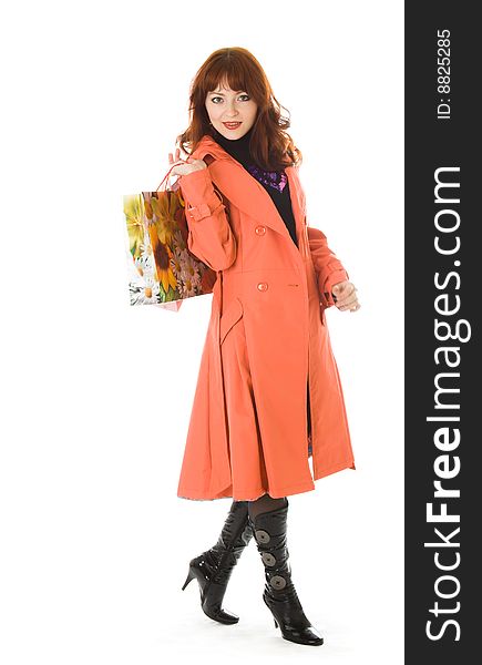 Beautiful woman in orange coat with bags. Isolated on white background