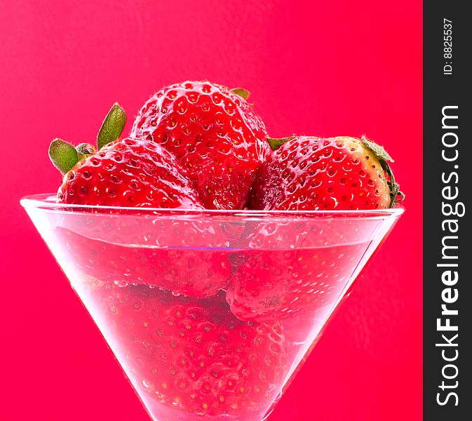 Strawberries in glass on pink background