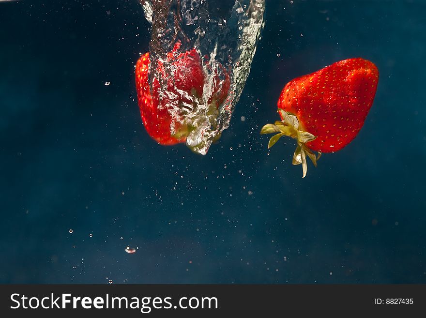 Fresh strawberries dropped into water