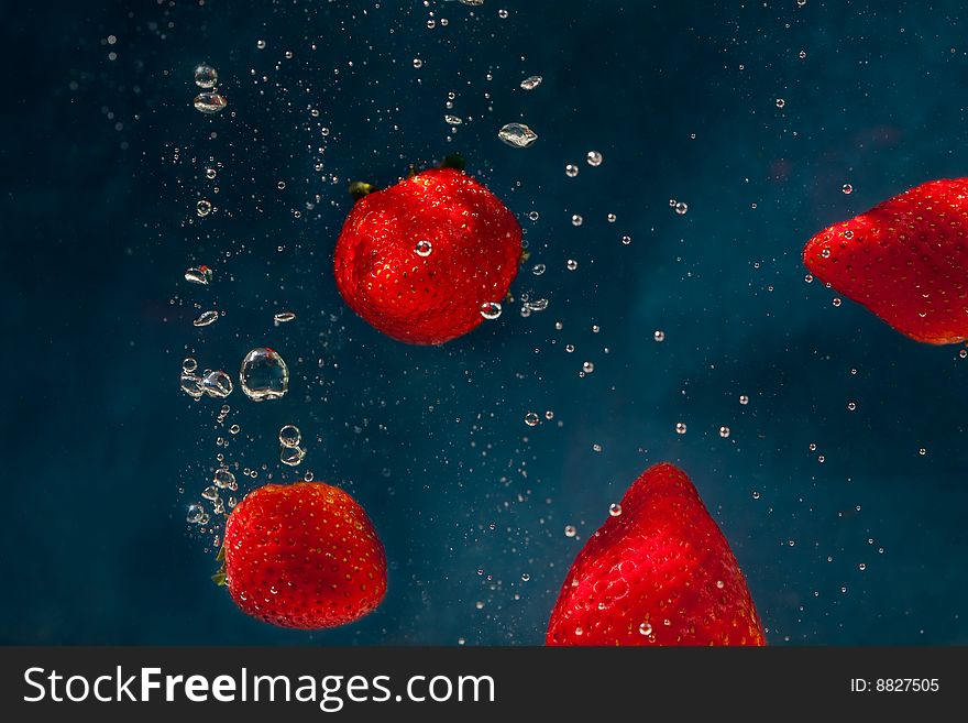 Fresh strawberries dropped into water