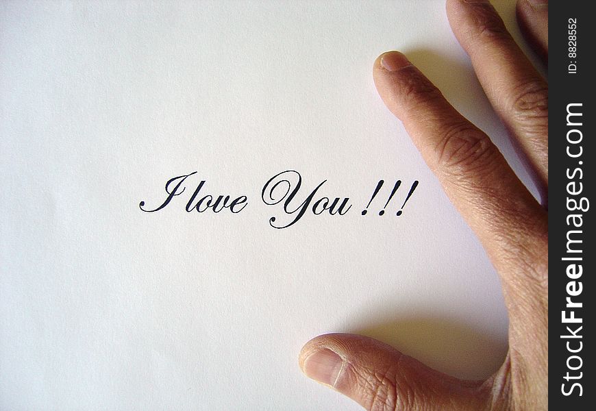 Close up view of the words I LOVE YOU written in classic type and a male hand on a white paper sheet