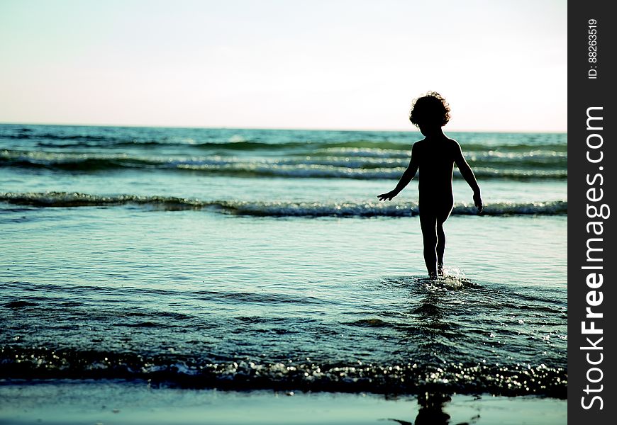 Child Walking On Seashore During Daytime