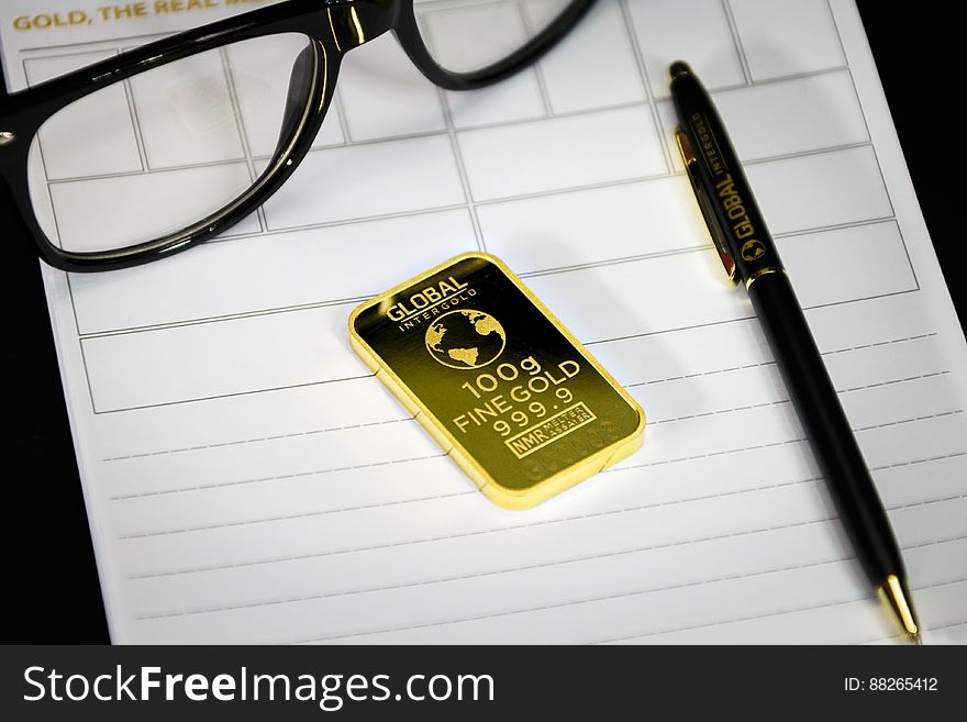Gold bar with pen and eyeglasses
