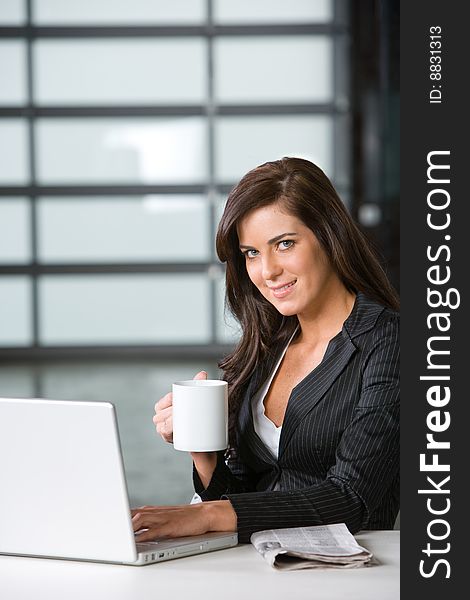 Business woman in modern office with laptop and coffee. Business woman in modern office with laptop and coffee