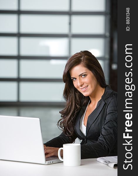 Business woman in modern office with laptop and coffee. Business woman in modern office with laptop and coffee