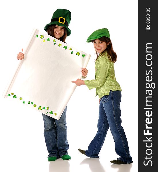 Two girls dressed for St. Patrick's Day. One holds a blank sign (for your message) with a shamrock border. The other points happily to it. Two girls dressed for St. Patrick's Day. One holds a blank sign (for your message) with a shamrock border. The other points happily to it.