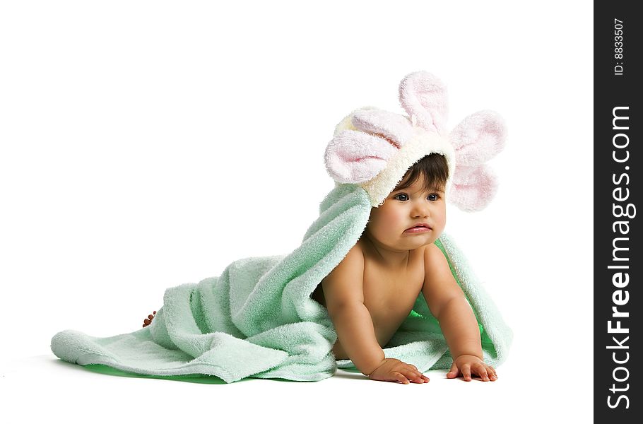 A biracial baby playing in a green towel with flower petals surrounding her head. Isolated on white. A biracial baby playing in a green towel with flower petals surrounding her head. Isolated on white.