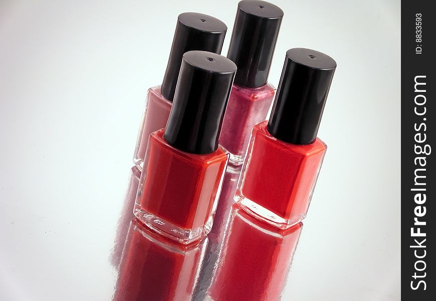 Four bottles of nailpolish on a reflecting surface
