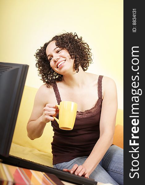 Cheerful young woman working at home with a cup of coffee. Cheerful young woman working at home with a cup of coffee