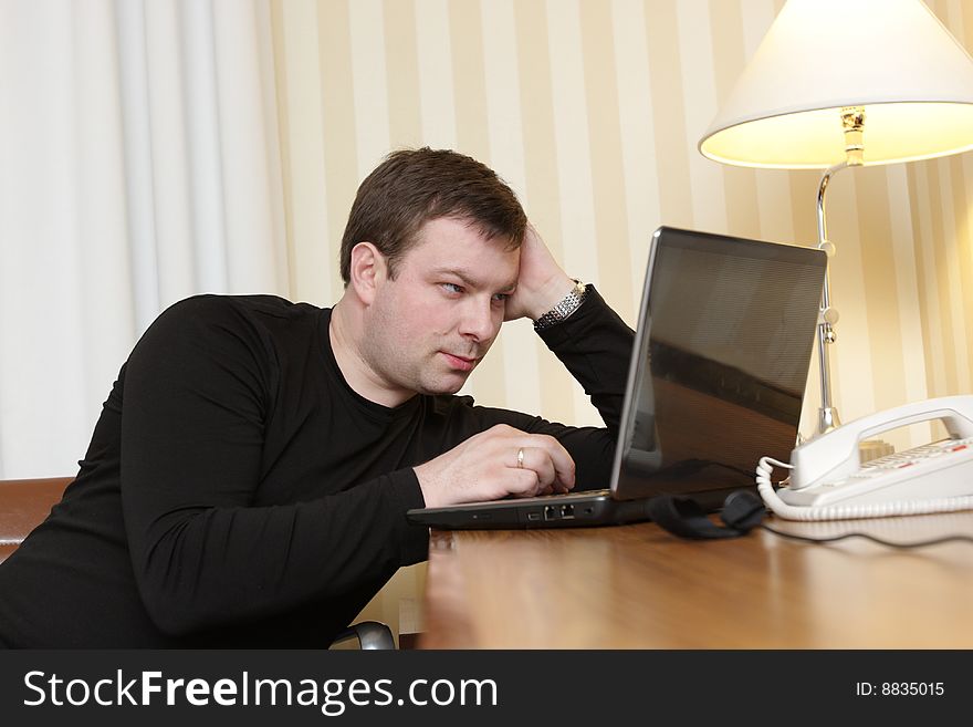 The man watches a film on laptop in a hotel. The man watches a film on laptop in a hotel