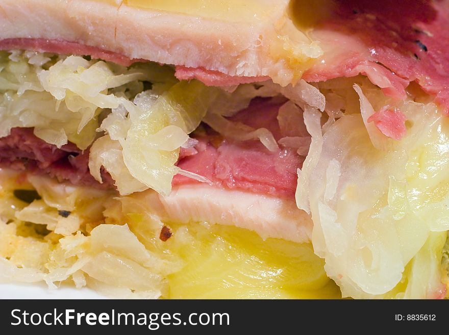 Extreme close up of a sandwich with melted cheese, sauerkraut and corned beef