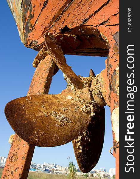 Ship propeller in a dock and a town on a background. Ship propeller in a dock and a town on a background