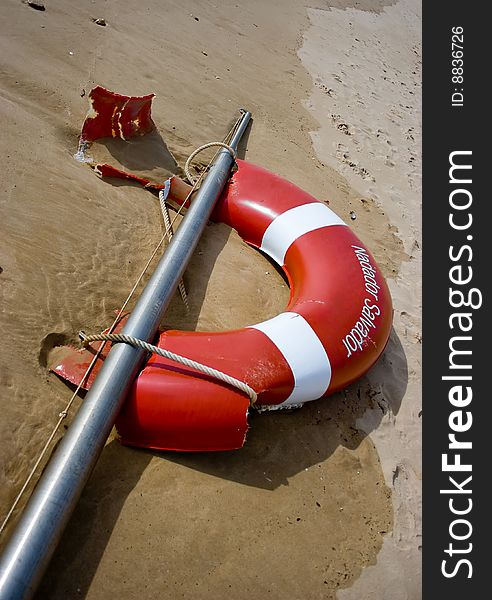Safety bouy on a metal pole laying on the ocean shore