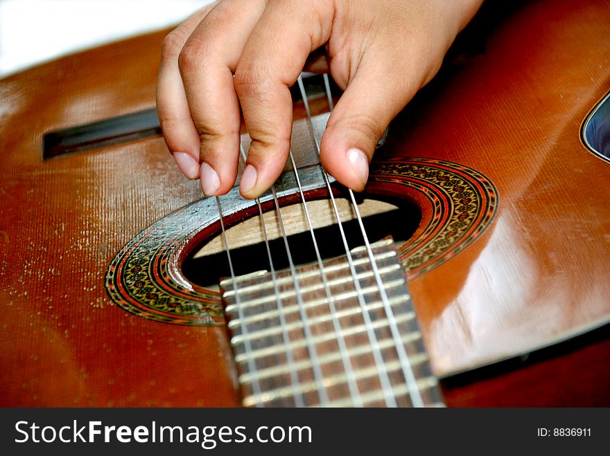 A hand touching the strings of the guitar