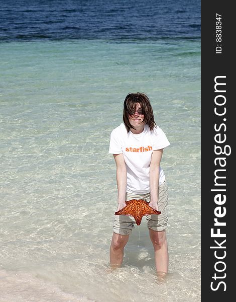 Woman with starfish shirt holding a red custion seastar starfish. Woman with starfish shirt holding a red custion seastar starfish