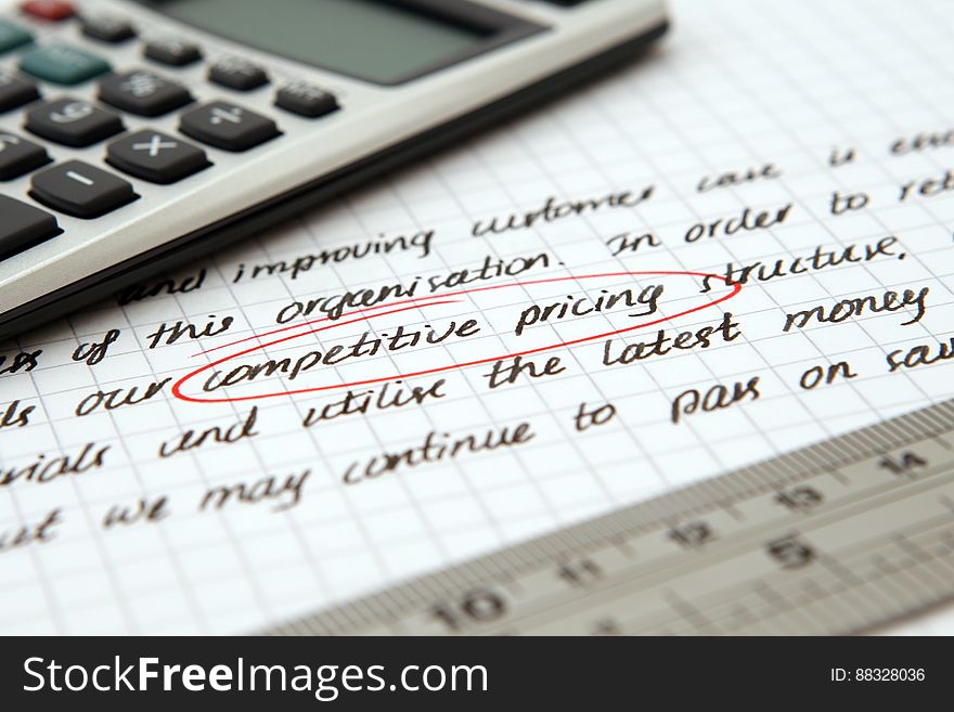 Competitive pricing circle in red on white sheet of paper with ruler and calculator. Competitive pricing circle in red on white sheet of paper with ruler and calculator.