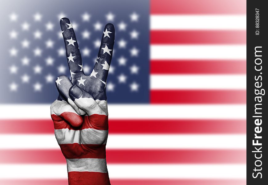 A person doing the V sign in front of the flag of the USA. A person doing the V sign in front of the flag of the USA.
