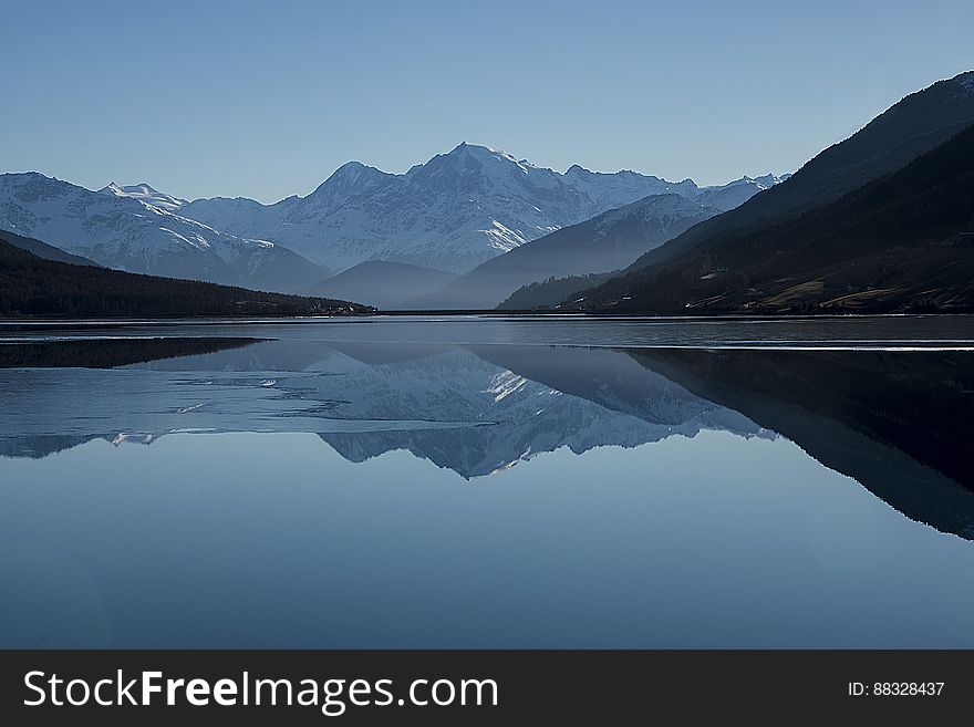 A clear lake with mountains reflecting from the surface. A clear lake with mountains reflecting from the surface.