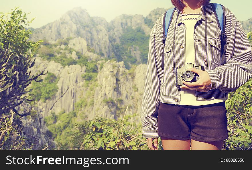 A traveler with a camera standing in front of a mountain landscape. A traveler with a camera standing in front of a mountain landscape.