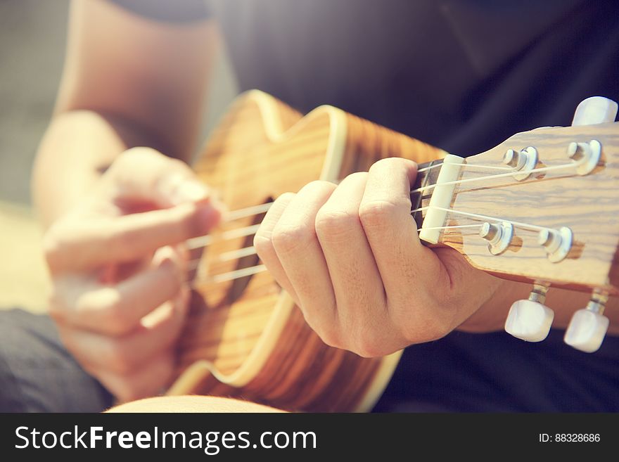 A close up of a man playing ukulele.