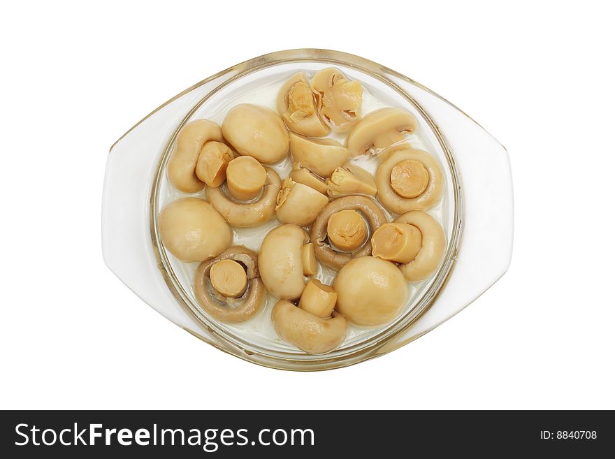 The tinned champignons in a plate are isolated on a white background