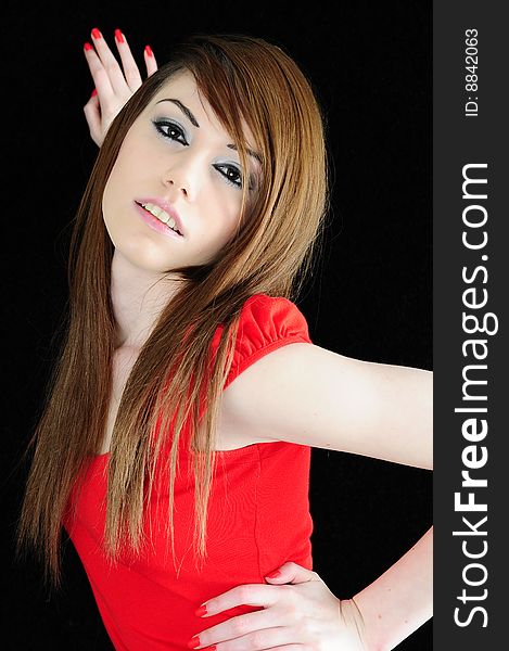 Female fashion model with strong facial make up and a bright red top. Shes standing against a black backdrop with long straight brunette hair. Female fashion model with strong facial make up and a bright red top. Shes standing against a black backdrop with long straight brunette hair