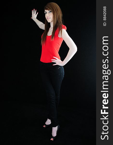 Female model standing in fashionable clothing against a black back drop with her hand on her hip. Female model standing in fashionable clothing against a black back drop with her hand on her hip