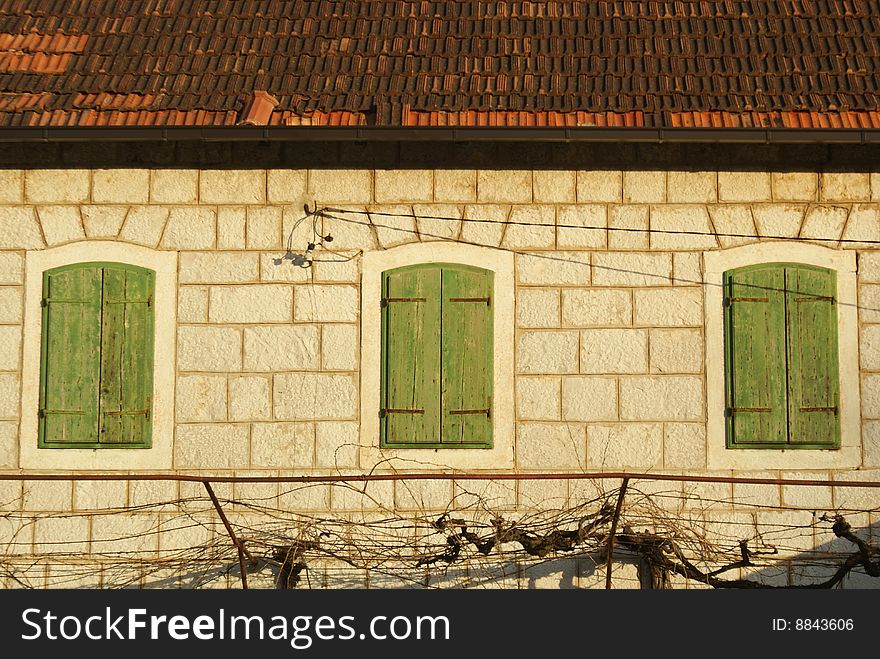Old stone house with green wooden windows.