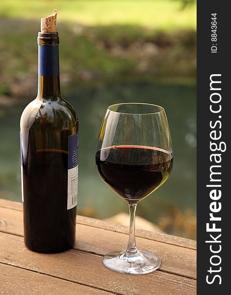 Bottle and glass of red wine outdoors