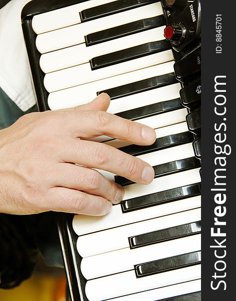 Musician hand playing accordion closeup in dramatic shadows