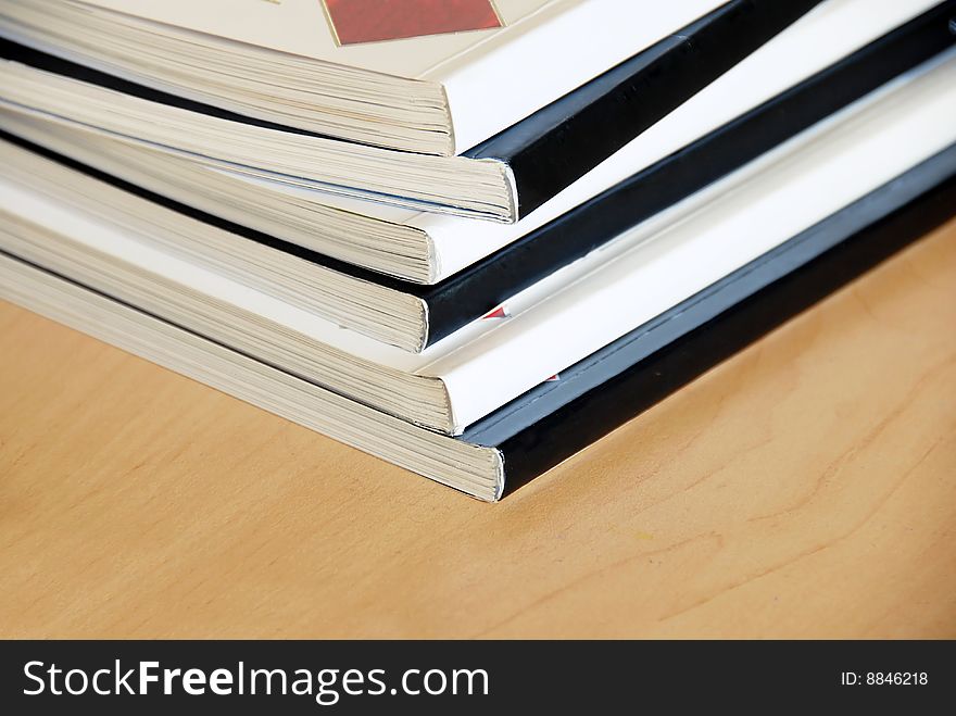 Black and white magazines pile closeup on wooden desk