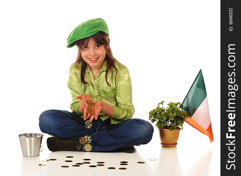 An older elementary girl dressed for St. Patrick's Day while displaying a handful of gold coins.  A golden pot of shamrocks and an Irish flag are nearby. An older elementary girl dressed for St. Patrick's Day while displaying a handful of gold coins.  A golden pot of shamrocks and an Irish flag are nearby.