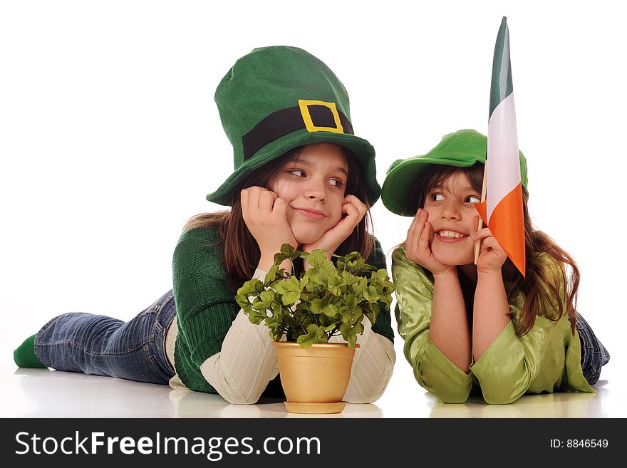 Two girls in green celebrating St. Patrick's Day with a gold pot of clover and an Irish flag. Isolated on white. Two girls in green celebrating St. Patrick's Day with a gold pot of clover and an Irish flag. Isolated on white.