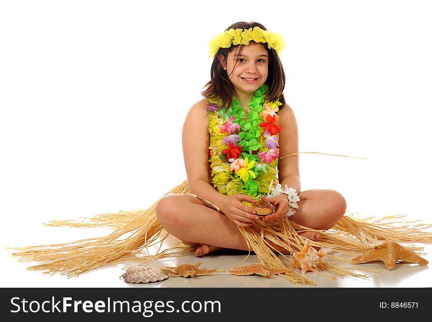 A preteen girl dressed in Hawaiian leis and a grass skirt sitting among star fish and shells. Isolated on white. A preteen girl dressed in Hawaiian leis and a grass skirt sitting among star fish and shells. Isolated on white.