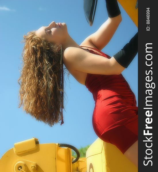 woman in red dress hangs from construction machinery. woman in red dress hangs from construction machinery